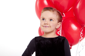 Cute little girl holding a bunch of red heart-shaped balloons