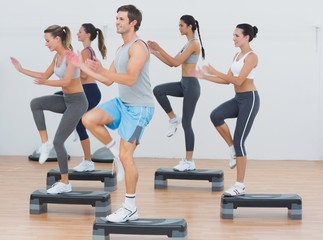 Fitness class performing step aerobics exercise