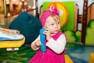 Happy child girl talking on the phone on playground.