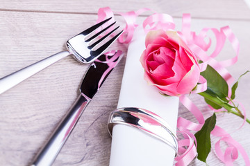 romantisch gedeckter tisch mit silberbesteck und einer rose