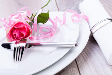romantisch gedeckter tisch mit silberbesteck und einer rose