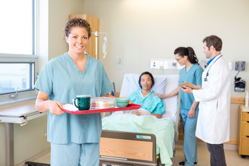 Obraz premium Nurse Holding Tray With Medical Team And Patient In Background