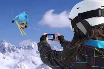 Fototapete Young girl by mobile phone photographs of skiers jump © smuki