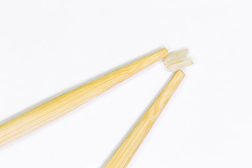 two wooden chopsticks for sushi and two grains of rice