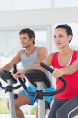 Fototapeta na wymiar Determined couple working out at spinning class in gym