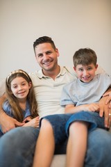 Father with son and daughter smiling on sofa