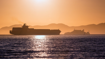 Alcatraz island penitentiary at sunset and merchant ship
