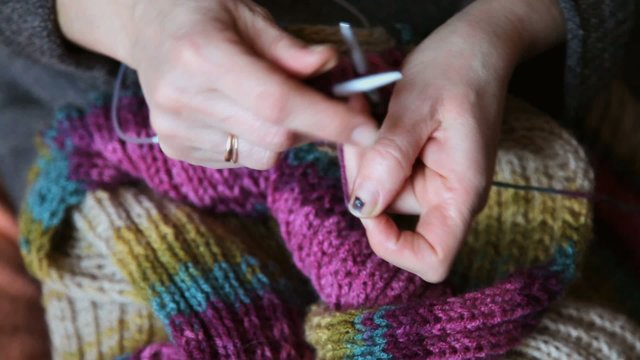 Woman hands knitting wool scarf, closeup video