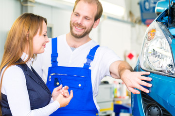 Kundin und Mechaniker an Auto in Werkstatt