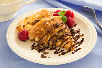 Delicious pancakes with berries and chocolate sauce.