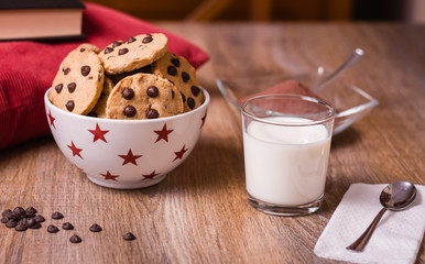 Chocolate chip cookies and milk on wood background