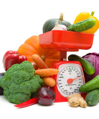 kitchen scale and vegetables on a white background