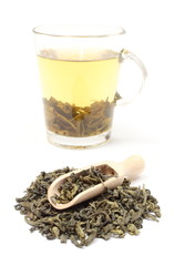 Heap of green tea and cup of beverage. White background