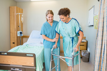 Nurse Helping Patient To Walk Using Walker In Hospital