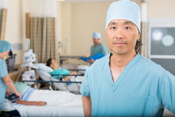 Male Nurse With Colleagues Examining Patient's In Ward