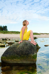 Attractive woman sitting on a rock on the beach