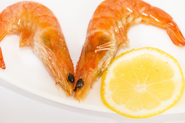two shrimp with lemon on a plate