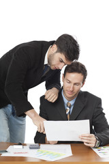 Two businessmen using paper at desk in office