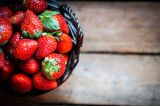 Basket of fresh strawberries on wooden background