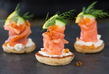 Blini with smoked salmon and sour cream, garnished with dill. Cl
