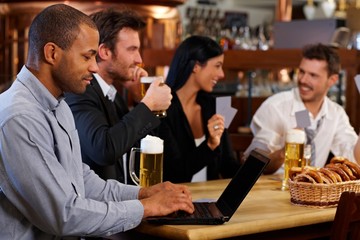 Young man using laptop at pub