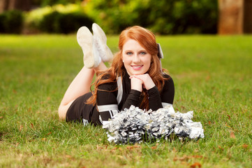 beautiful young red headed female cheerleader lying in the grass