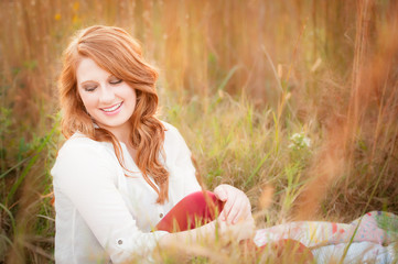 beautiful young red haired female in a field smiling