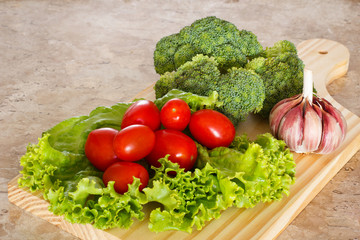 Fresh broccoli, tomatoes and garlic on wooden board