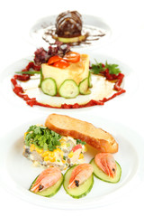Small portions of food on big white plates isolated on white