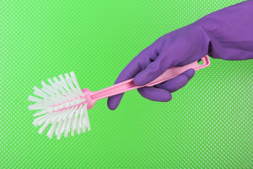 Toilet brush in hand on green background
