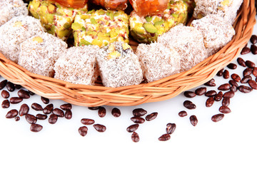 Tasty oriental sweets on wicker tray, isolated on white
