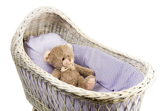 Toy bear in a romantic vintage wicker crib with cushion