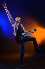 Young musician playing  guitar on dark color background