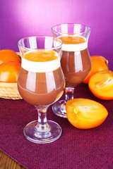 Dessert of chocolate and persimmon on table on purple