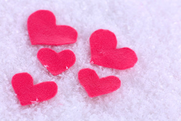 Obraz premium Little felt hearts on snowy background