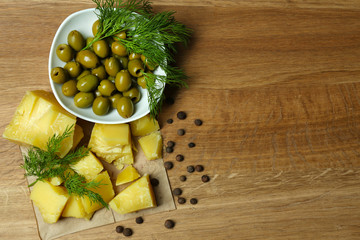 Parmesan cheese, fresh herbs and olives on wooden background