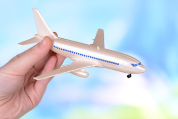 Toy airplane in hand on light blue background