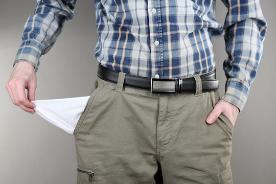 Man showing his empty pocket on grey background
