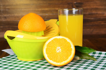 Citrus press and oranges on table on wooden background