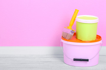 Paints and paintbrush on floor in room on wall background