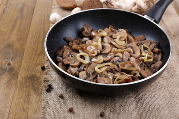 Delicious fried mushrooms in pan on table close-up