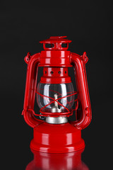 Red kerosene lamp on black background