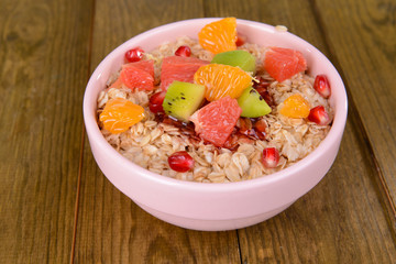 Delicious oatmeal with fruit in bowl on table close-up