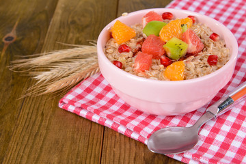 Delicious oatmeal with fruit in bowl on table close-up