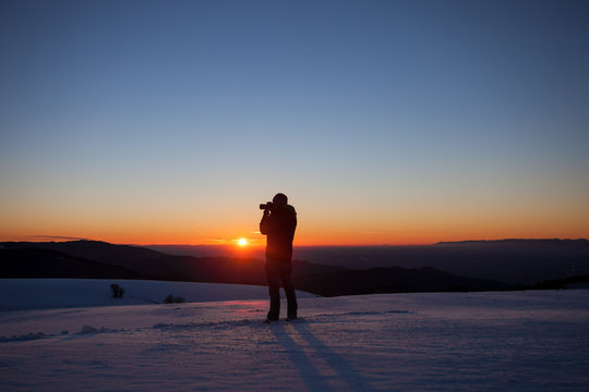silhouette of photographer in sunset in winter landscape