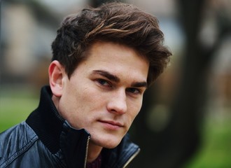 Young stylish guy in park posing