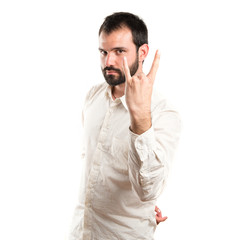 Young man doing the horn sign over white background