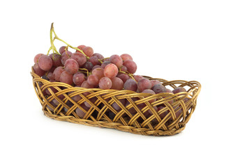 Red grape on branch in brown wicker basket isolated
