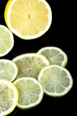 slices of lime and lemon on black background