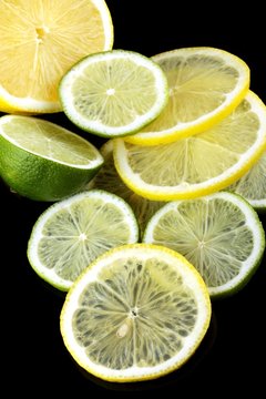 slices of lime and lemon on black background